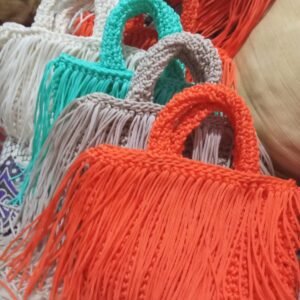 Handcrafted fringe tote bags arranged in an overlapping cascade