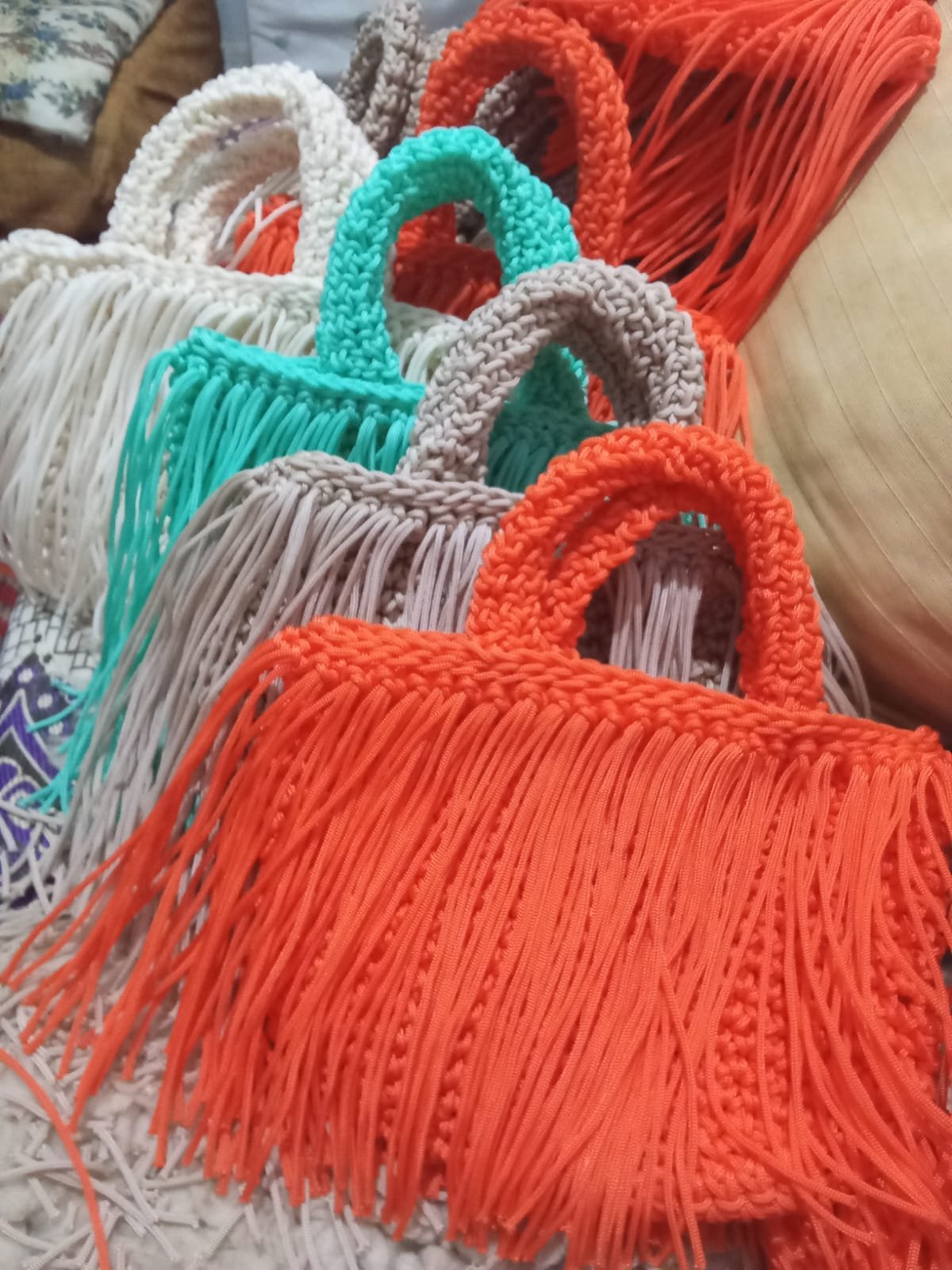 Handcrafted fringe tote bags arranged in an overlapping cascade